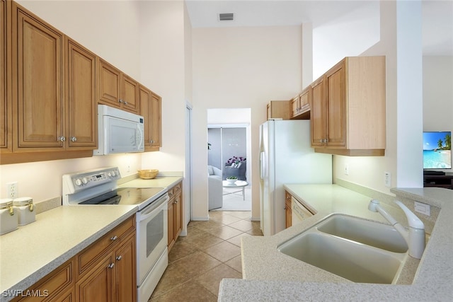 kitchen with a high ceiling, white appliances, sink, and light tile patterned flooring