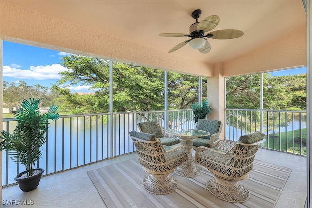 sunroom featuring ceiling fan, plenty of natural light, a water view, and vaulted ceiling