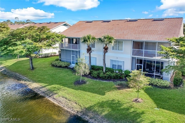 rear view of house featuring a balcony, a yard, and a water view