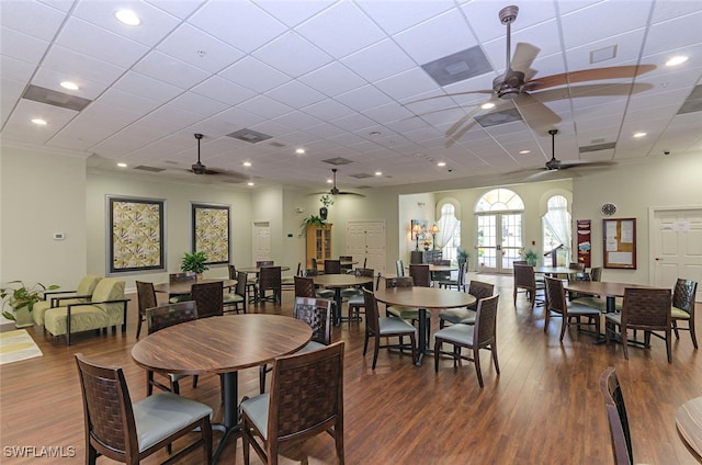 dining space with dark wood-type flooring, a drop ceiling, ceiling fan, and crown molding