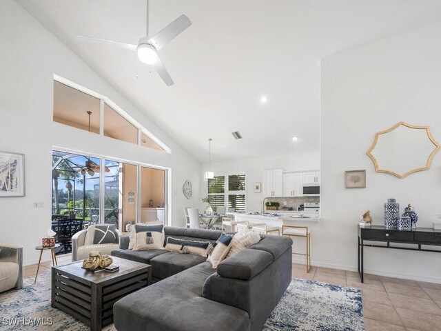 tiled living room with ceiling fan and high vaulted ceiling