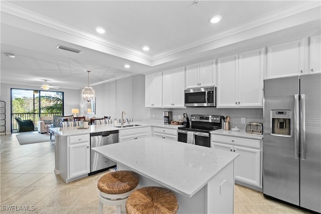 kitchen with a center island, kitchen peninsula, hanging light fixtures, sink, and appliances with stainless steel finishes