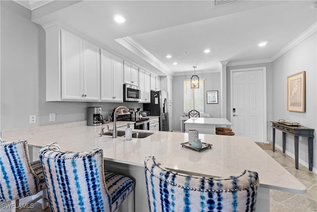 kitchen featuring kitchen peninsula, a kitchen bar, ornamental molding, and stainless steel appliances