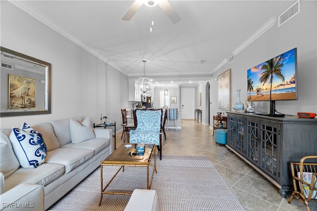 living room with light tile patterned floors, ornamental molding, and ceiling fan with notable chandelier