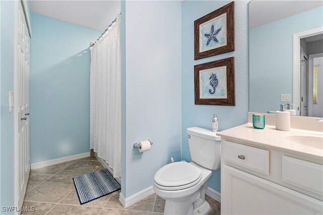 bathroom with toilet, vanity, and tile patterned flooring