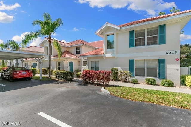 view of front of house featuring covered parking, a tile roof, and stucco siding