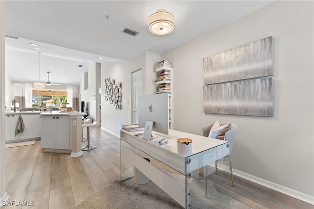 home office featuring light hardwood / wood-style flooring and sink