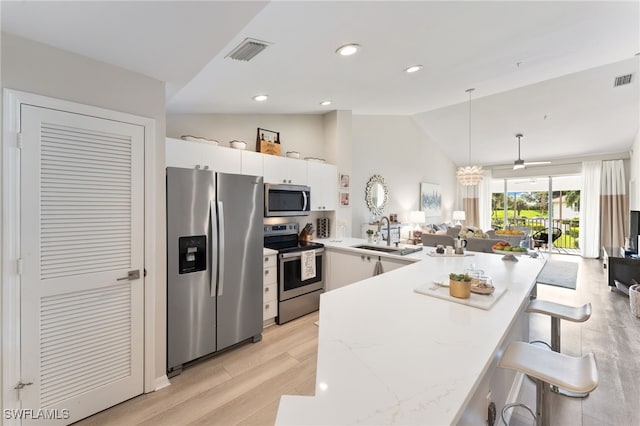 kitchen featuring appliances with stainless steel finishes, white cabinetry, hanging light fixtures, and lofted ceiling