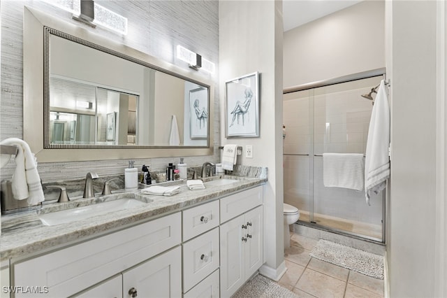 bathroom featuring tile patterned flooring, vanity, toilet, and a shower with door