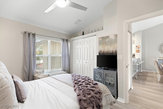 bedroom featuring ceiling fan, a closet, light hardwood / wood-style floors, and lofted ceiling