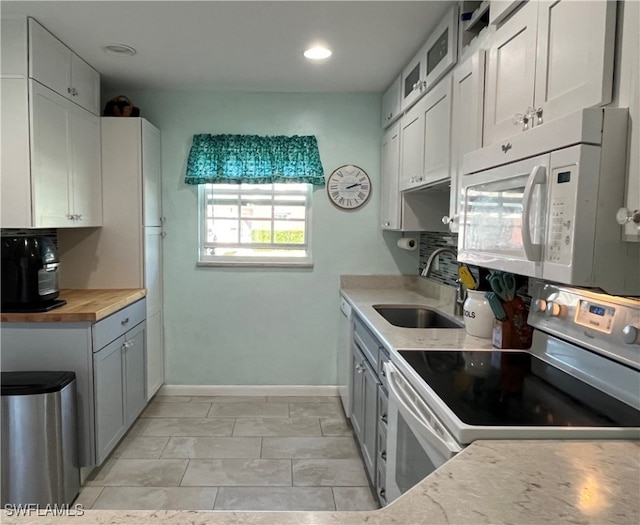 kitchen featuring wooden counters, white appliances, a sink, and white cabinets