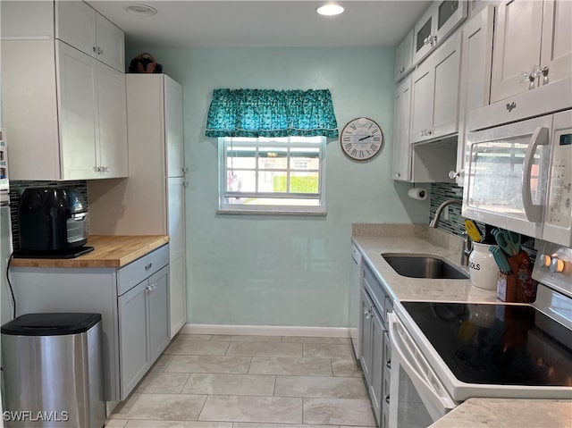 kitchen featuring white cabinetry, butcher block counters, white appliances, and sink