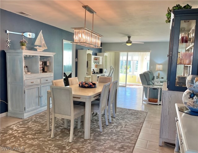 tiled dining room with ceiling fan with notable chandelier