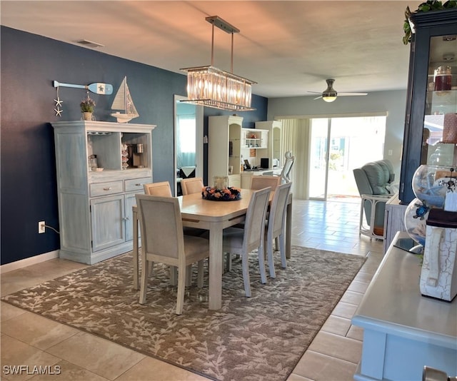 tiled dining area with ceiling fan with notable chandelier