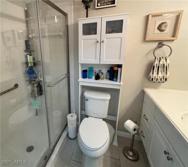 bathroom with tile patterned flooring, vanity, toilet, and a shower with shower door