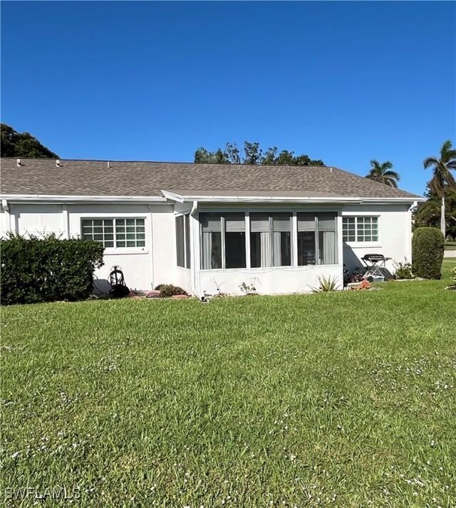 1374 Bunker Way, Fort Myers, FL 33919 - rear view of property with a yard, stucco siding, roof with shingles, and a sunroom