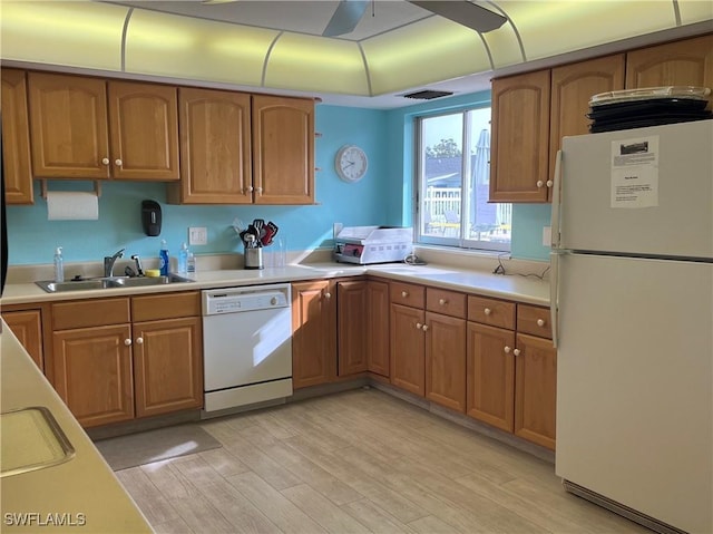 kitchen featuring white appliances, a sink, visible vents, light countertops, and brown cabinetry