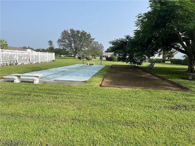 surrounding community featuring fence, a lawn, and shuffleboard