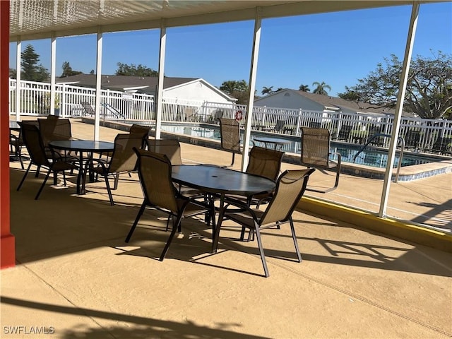 view of patio featuring outdoor dining area, a residential view, fence, and a community pool