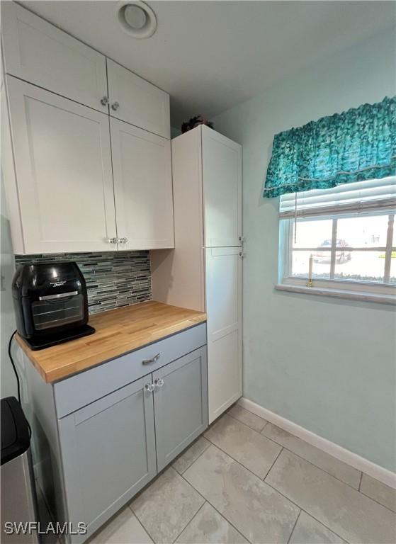1374 Bunker Way, Fort Myers, FL 33919 - kitchen featuring wooden counters, tasteful backsplash, baseboards, and white cabinetry
