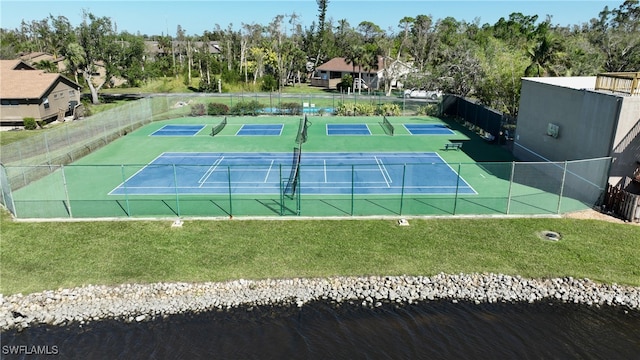 view of tennis court featuring a lawn and a water view