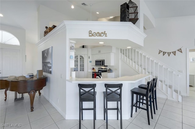 kitchen featuring kitchen peninsula, high vaulted ceiling, and stainless steel appliances