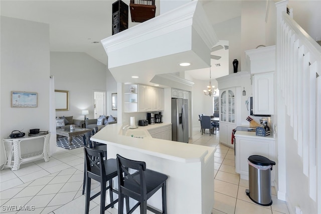 kitchen with kitchen peninsula, appliances with stainless steel finishes, a kitchen bar, light tile patterned floors, and an inviting chandelier