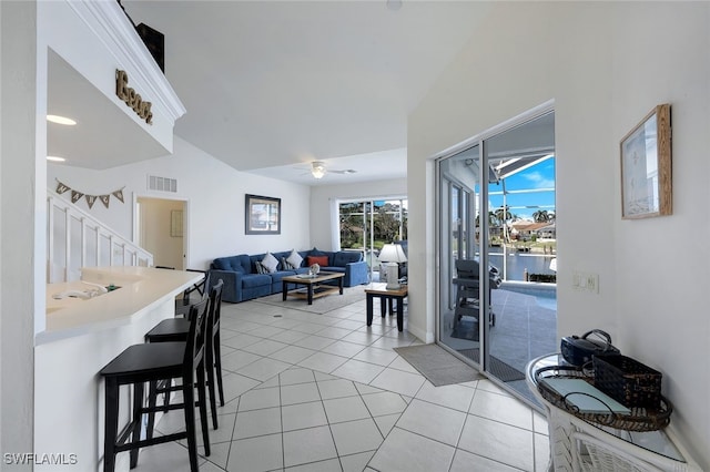 interior space with a water view, ceiling fan, and light tile patterned flooring