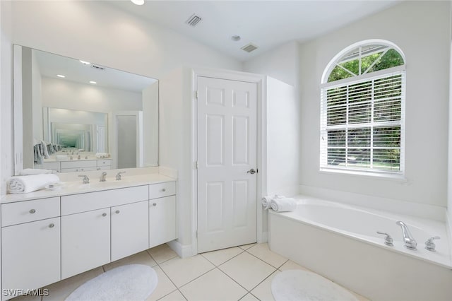 bathroom featuring lofted ceiling, vanity, tile patterned floors, and a bathing tub