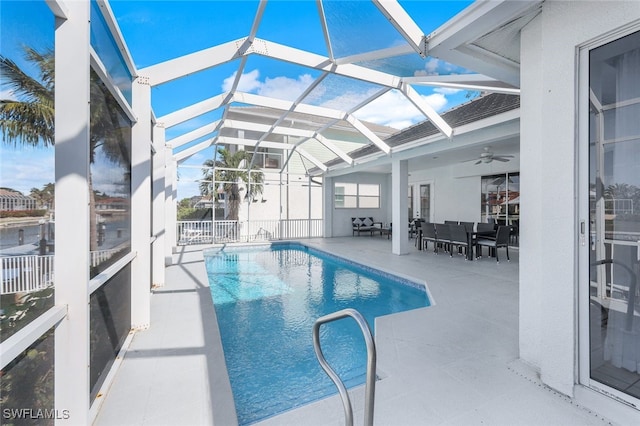 view of pool featuring glass enclosure, ceiling fan, and a patio