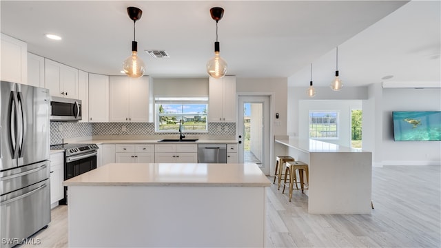 kitchen featuring light hardwood / wood-style flooring, a wealth of natural light, appliances with stainless steel finishes, and white cabinets