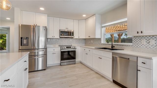 kitchen with a wealth of natural light, appliances with stainless steel finishes, sink, and light hardwood / wood-style floors