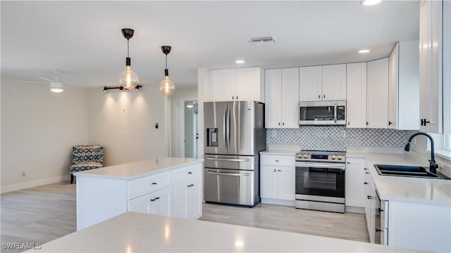 kitchen featuring pendant lighting, white cabinets, sink, and stainless steel appliances