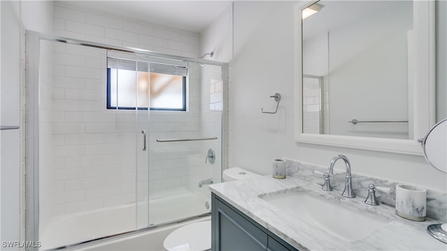 full bathroom with bath / shower combo with glass door, vanity, and toilet