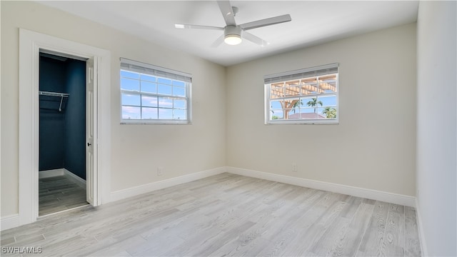 unfurnished bedroom featuring a closet, a walk in closet, multiple windows, and ceiling fan