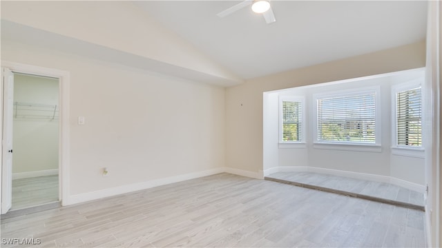 spare room featuring light hardwood / wood-style floors, lofted ceiling, and ceiling fan