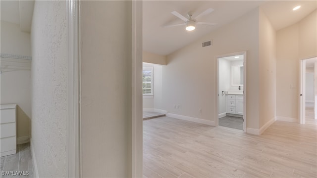 corridor featuring light wood-type flooring and vaulted ceiling