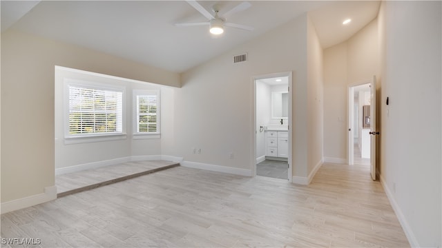 unfurnished bedroom with ceiling fan, connected bathroom, light hardwood / wood-style flooring, and high vaulted ceiling