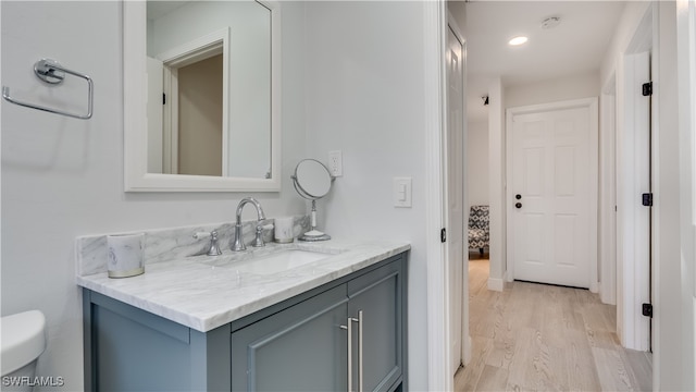 bathroom with hardwood / wood-style floors, vanity, and toilet