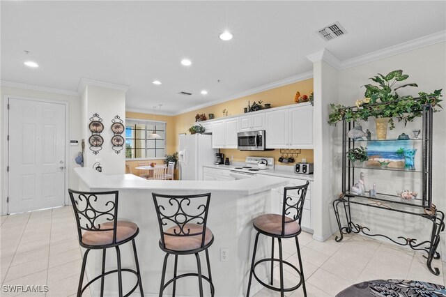 kitchen featuring ornamental molding, white cabinetry, kitchen peninsula, a kitchen bar, and white appliances