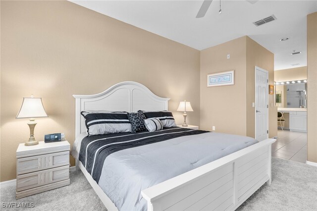 bedroom with connected bathroom, light carpet, and ceiling fan