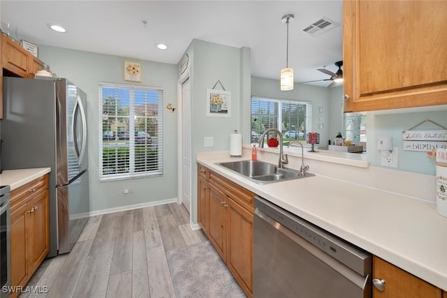 kitchen with ceiling fan, appliances with stainless steel finishes, decorative light fixtures, light wood-type flooring, and sink