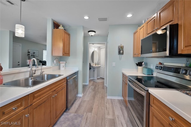 kitchen with hanging light fixtures, sink, stainless steel appliances, and light hardwood / wood-style flooring