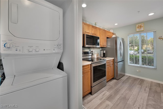 kitchen featuring light wood-type flooring, stacked washer and dryer, and stainless steel appliances