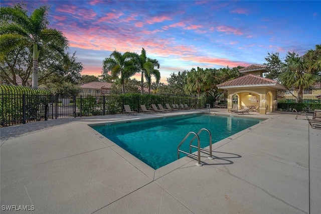 pool at dusk featuring a patio