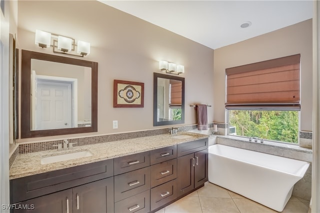 bathroom with tile patterned floors, a washtub, and vanity