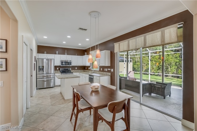 dining room featuring light tile patterned floors, ornamental molding, and sink