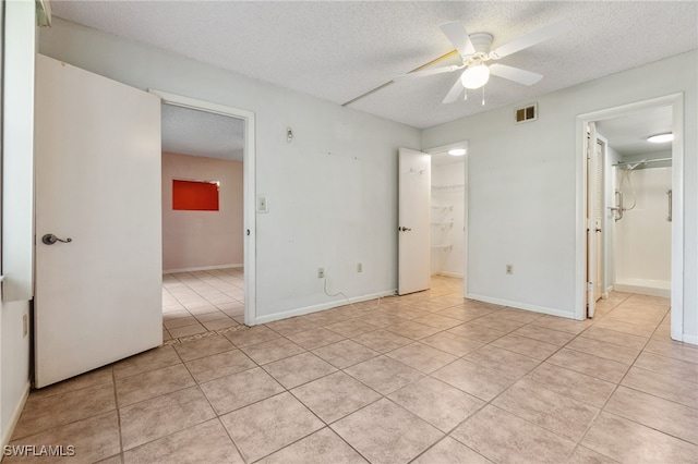 tiled empty room with ceiling fan and a textured ceiling