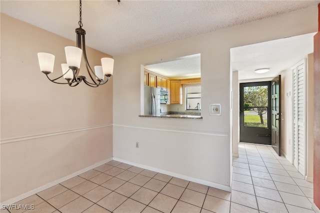 unfurnished dining area with light tile patterned flooring, a textured ceiling, and an inviting chandelier