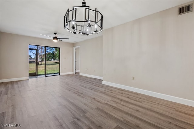 unfurnished dining area with ceiling fan with notable chandelier and light wood-type flooring